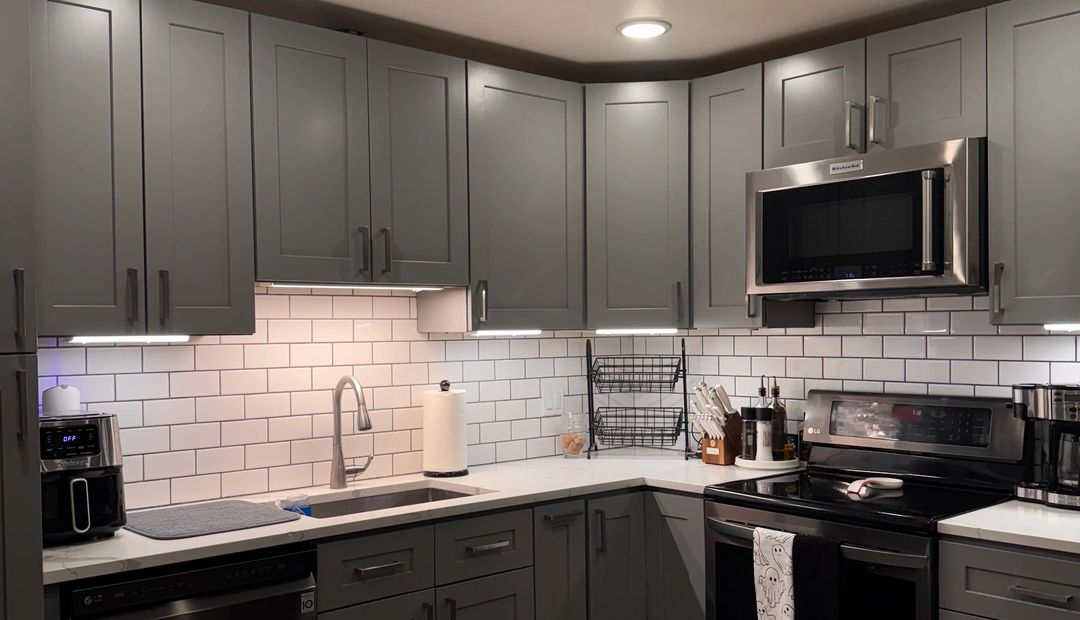 A clean modern kitchen with gray cabinets, white subway tile, and a clear counter — a job photo from Tidy Nest LLC.